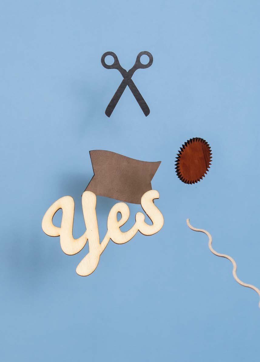 Yes-Schriftzug aus Holz mit Schere und Fahne auf blauem Grund